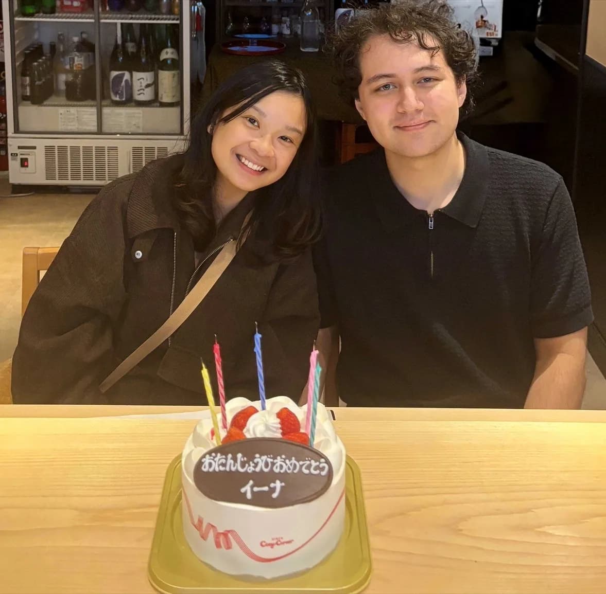A couple celebrating a birthday at the counter of REONA Sushi Tokyo, with a Japanese shortcake and its chocolate message plate