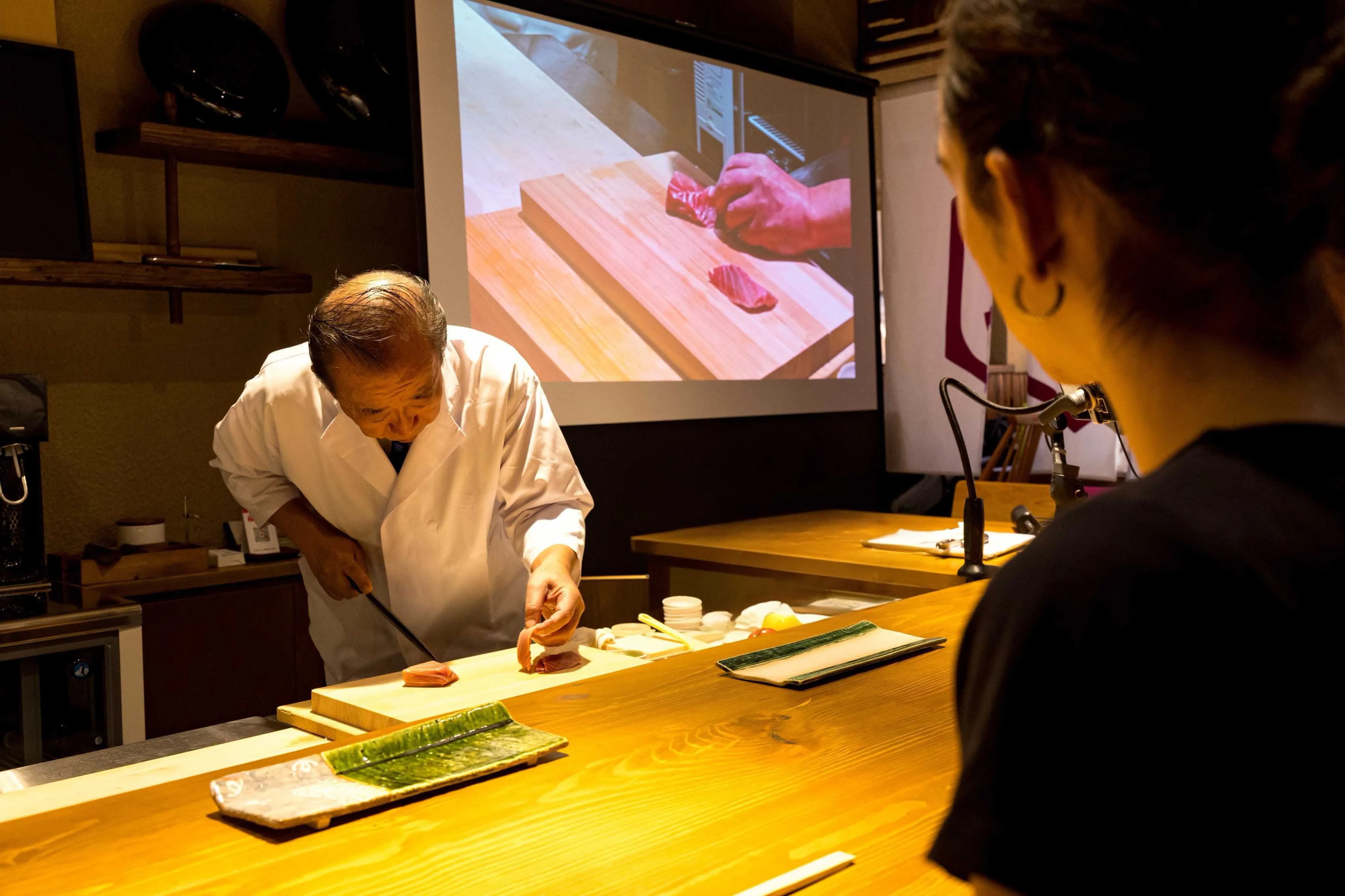 A chef at REONA Sushi Tokyo working with his knife at the cutting board