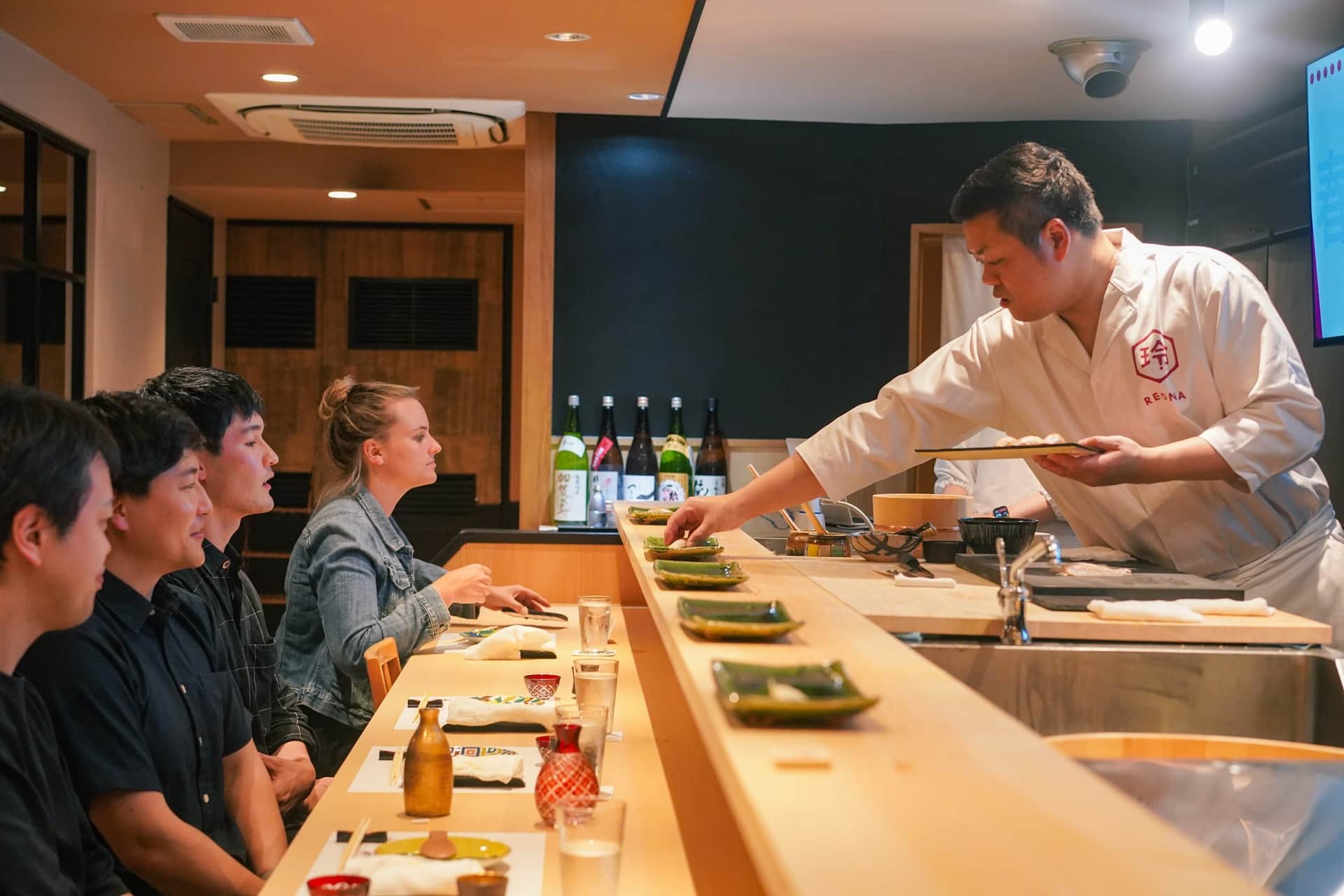 Guests enjoying an Edomae omakase experience at the counter of REONA Sushi Tokyo in Kanda