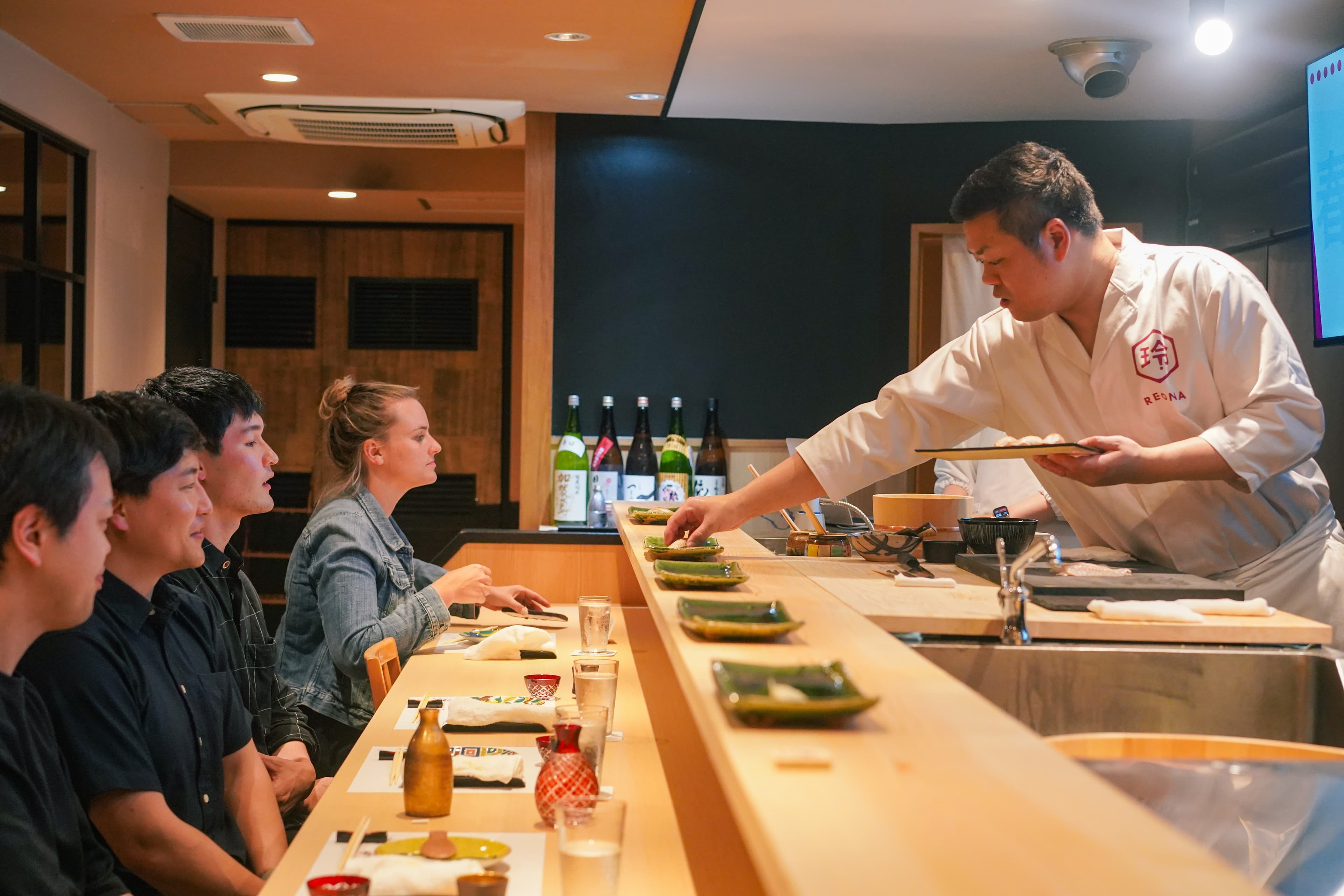 Guests enjoying an Edomae omakase experience at the counter of REONA Sushi Tokyo in Kanda