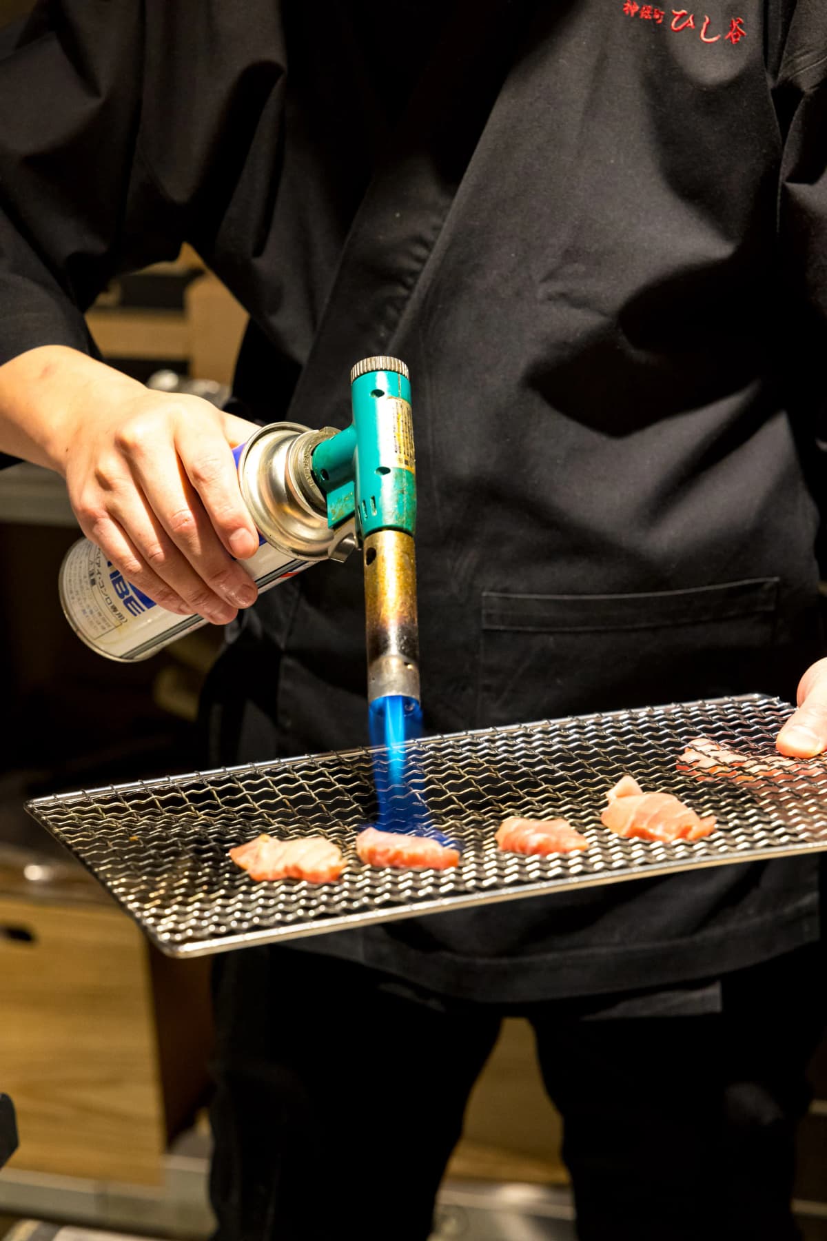 Searing premium otoro tuna with a torch at the counter
