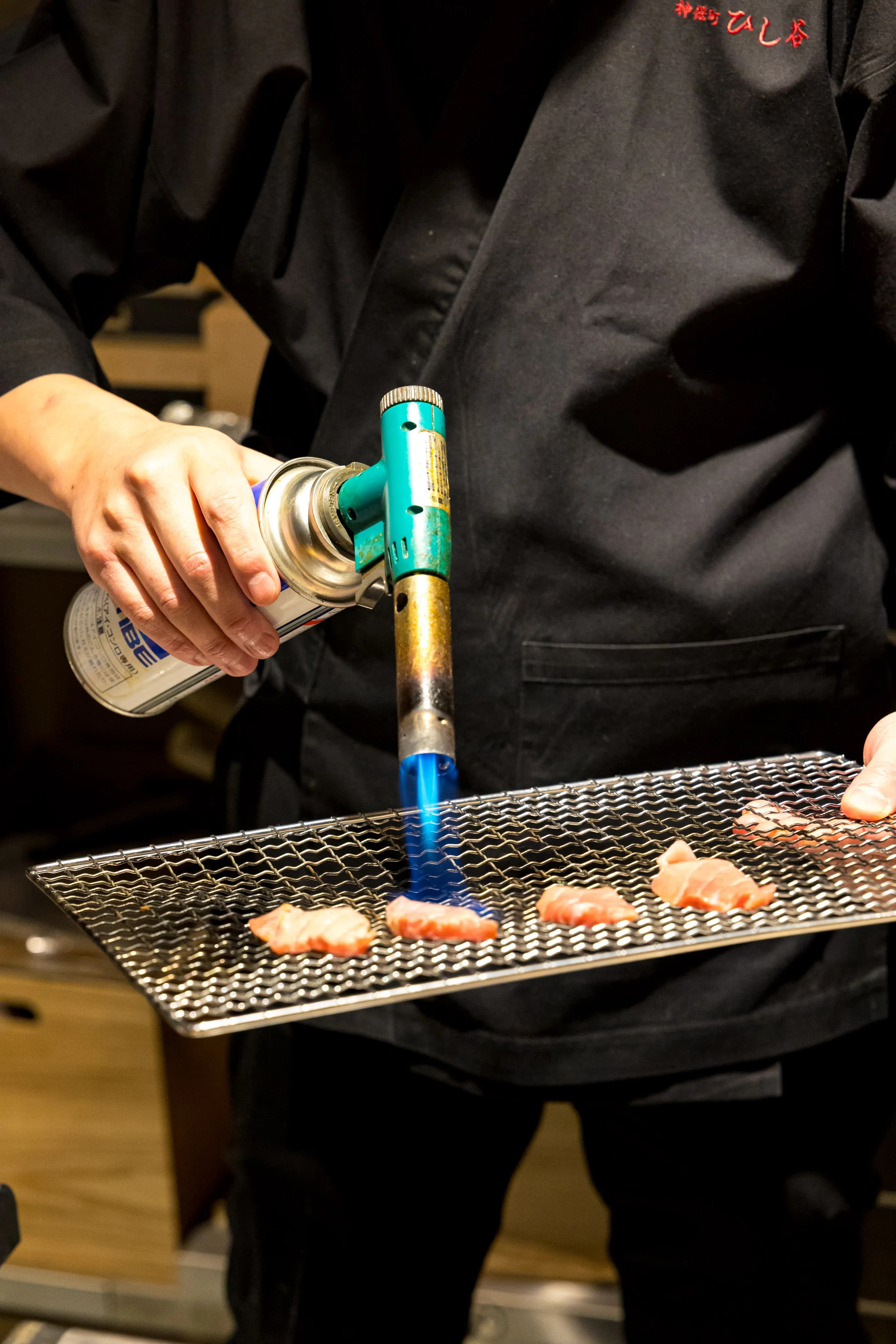 Searing premium otoro tuna with a torch at the counter