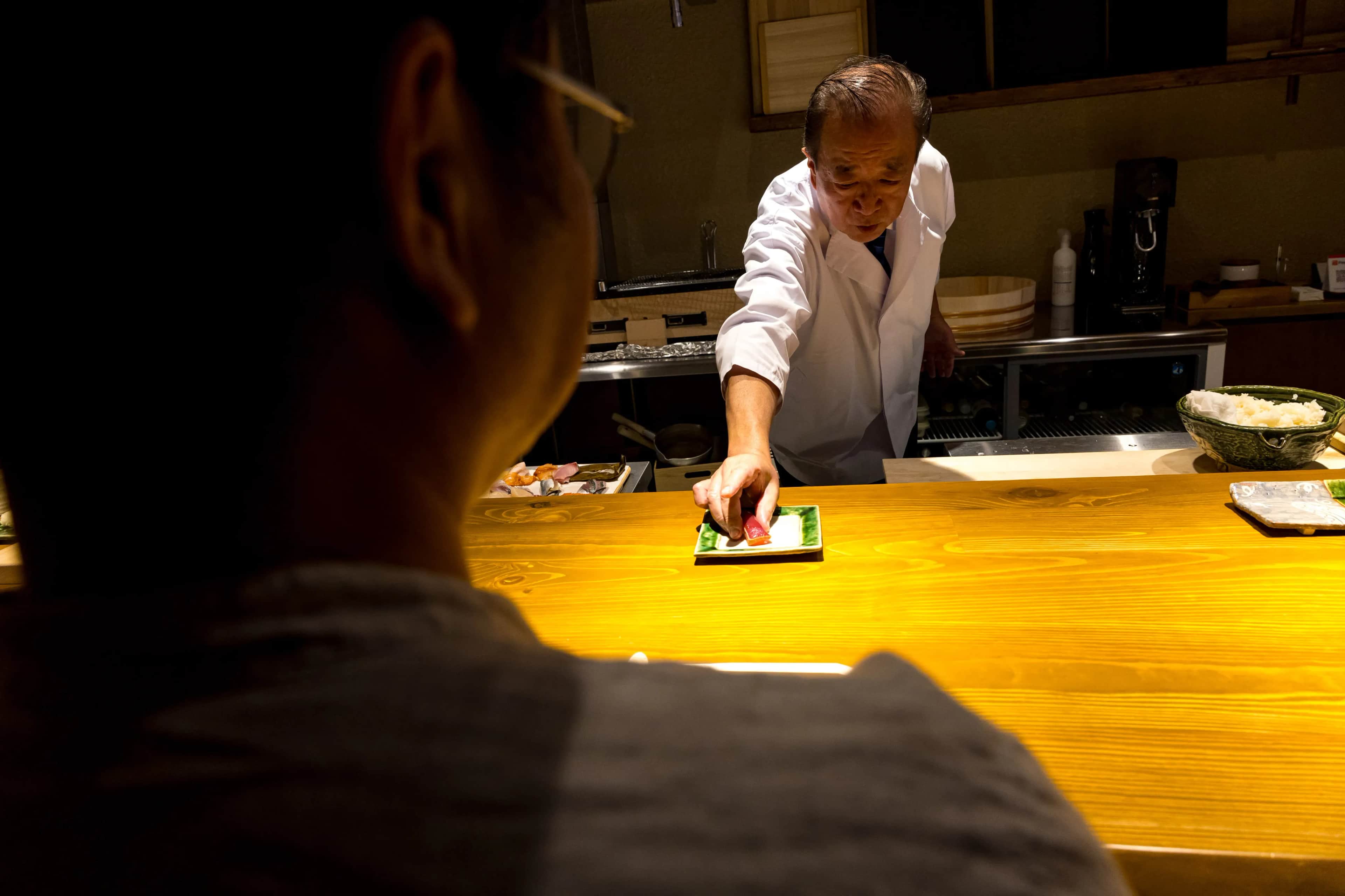 A sushi chef serving Edomae nigiri at REONA Sushi Tokyo in Kanda
